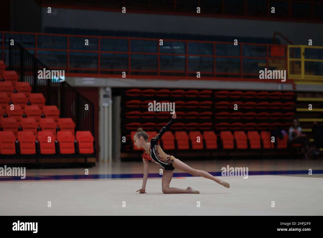 Young cute woman in gymnast suit show athletic skill. Empty sports stadium seats Stock Photo