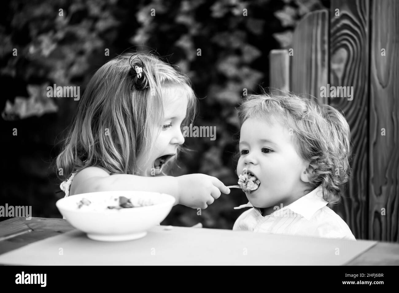 Sister feeding baby boy. Girl feeds brother with a spoon. Kid food ...