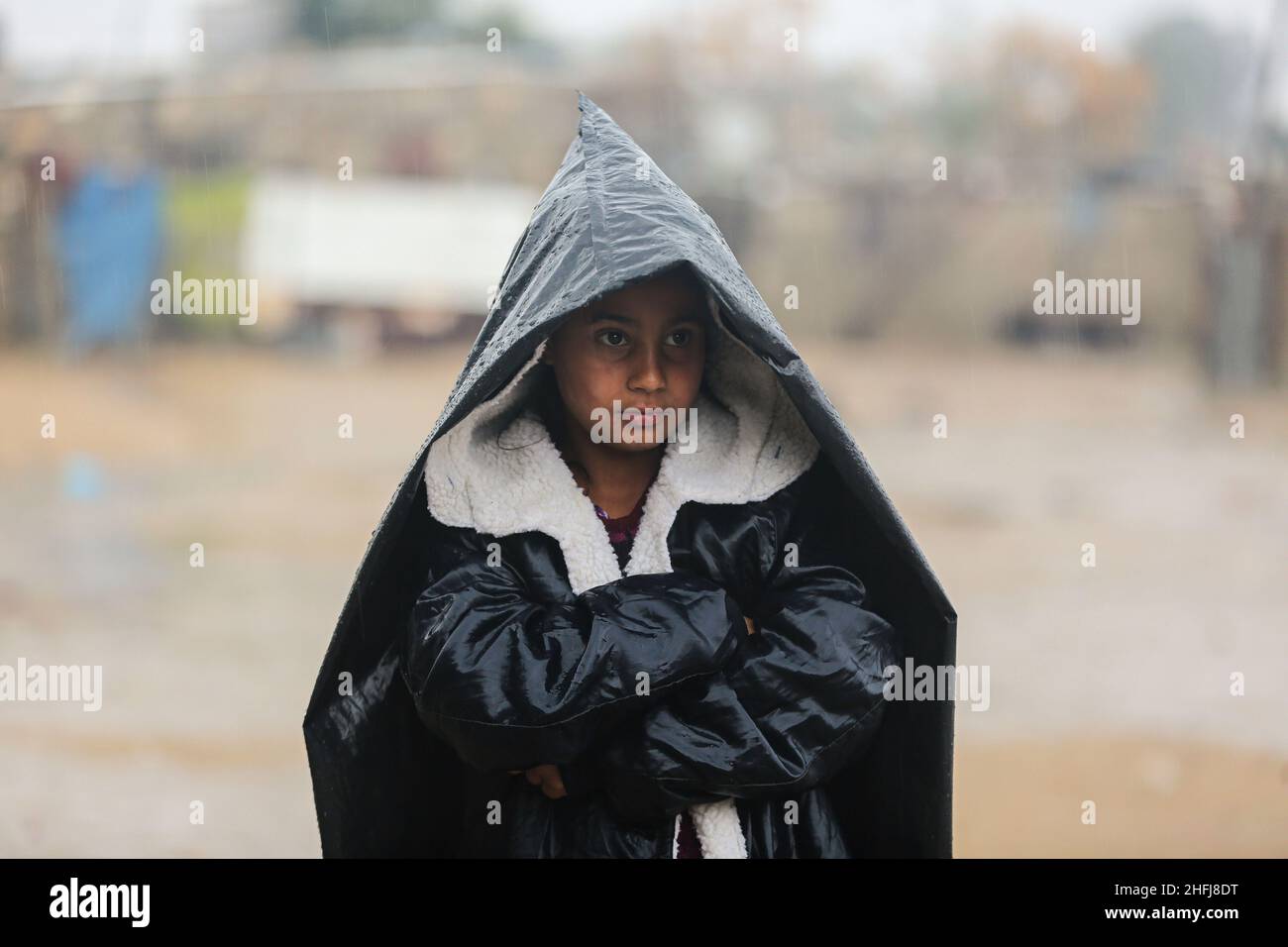 A Palestinian girl sheltering underneath a plastic sheet walks in front ...