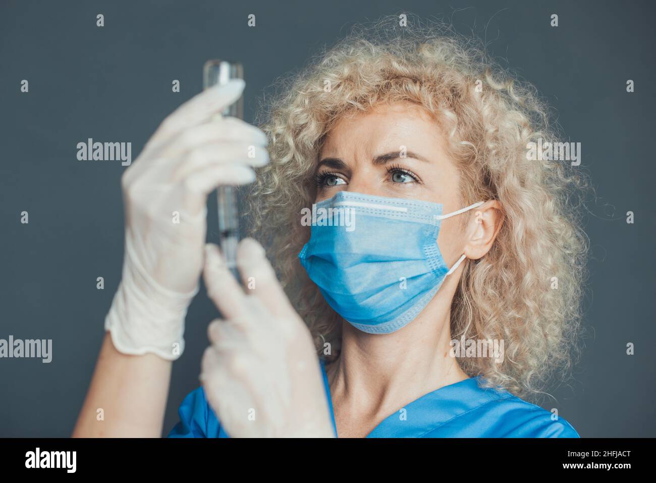 Close-up portrait of a female doctor in medical gloves and mask holding ...