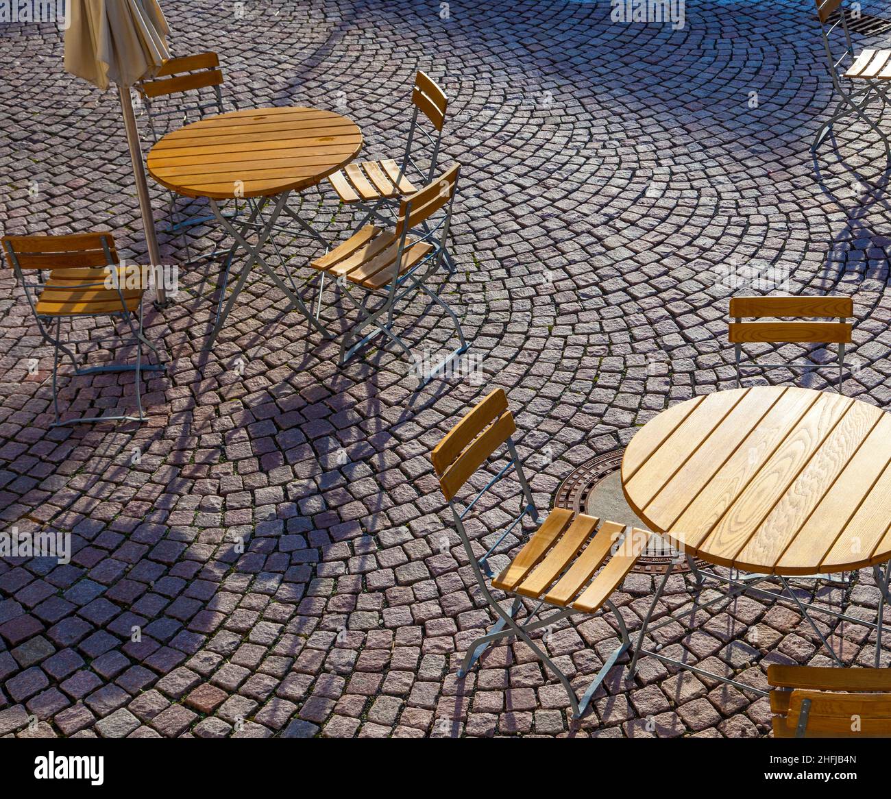 Outdoor German cafe seating with round tables and wooden chairs Stock Photo