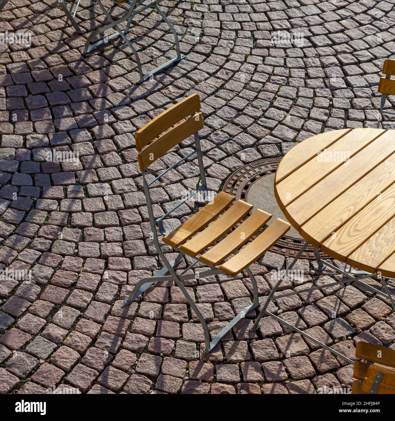 Outdoor German cafe seating with round tables and wooden chairs on