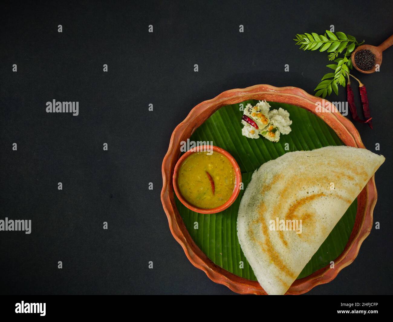 traditional south indian food masala dosa, sambar and coconut chutney served on clay plate and banana leaf. studio shot. copy space background. Stock Photo