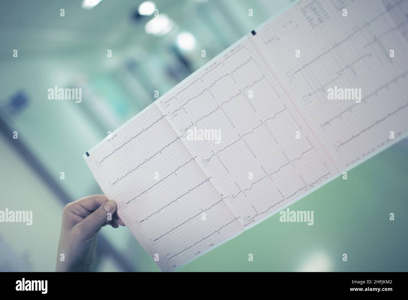 Female doctor examining the patient ECG result in the long hospital hallway. Stock Photo