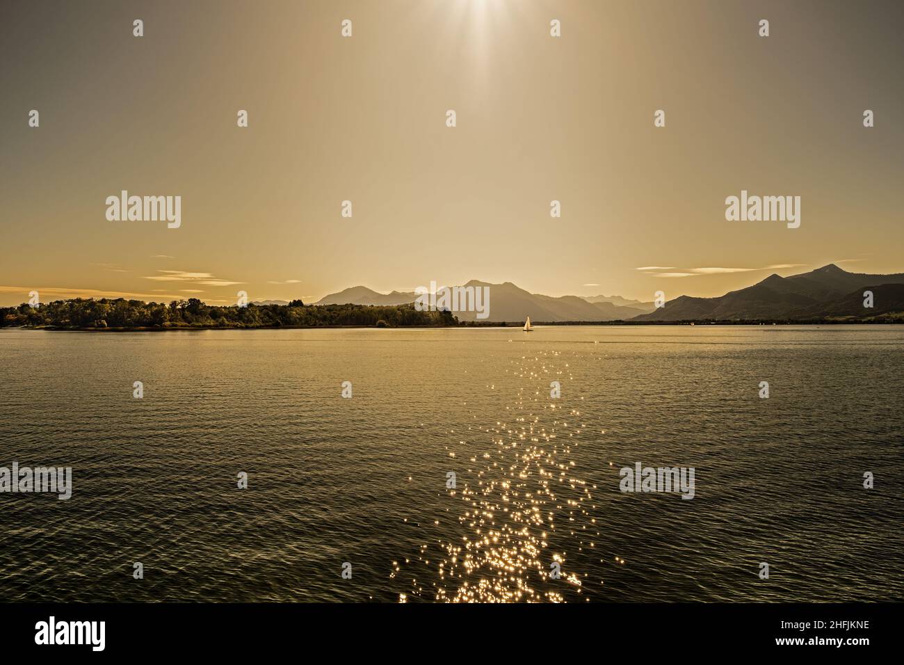 View of the Chiemsee with a sailing boat at sunset Stock Photo