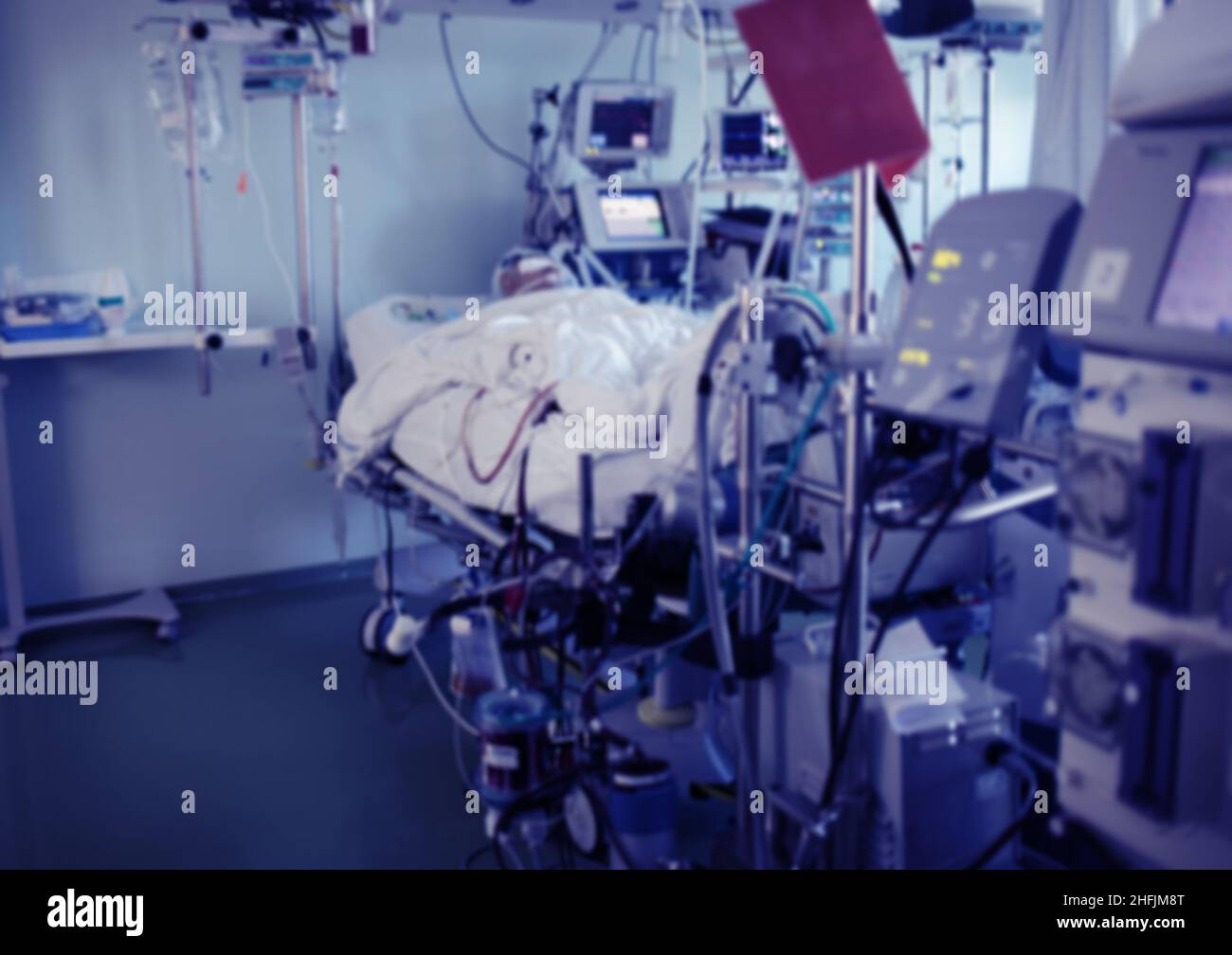 Critically ill comatose patient in the hospital bed connected to the advanced life support equipment in the ICU, unfocused background. Stock Photo