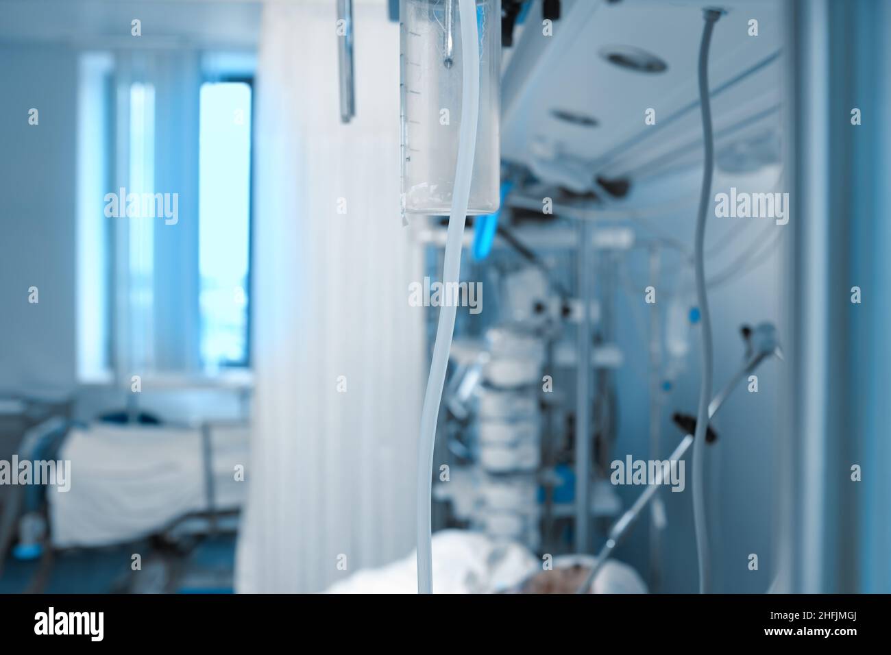 Hospital ward with life support equipment connected to the comatose patient, tube in the center of image as a concept of binding thread between patien Stock Photo
