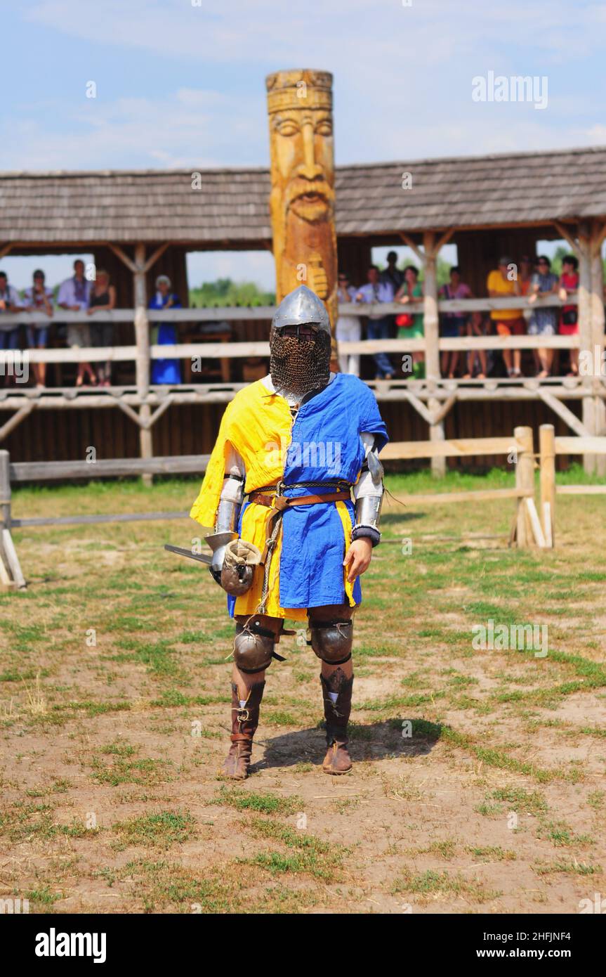 Kiev region, Ukraine. July 06.2013. A knight in armor with a sword, a reconstruction of a jousting tournament. Slavic pagan idol, scene with spectator Stock Photo