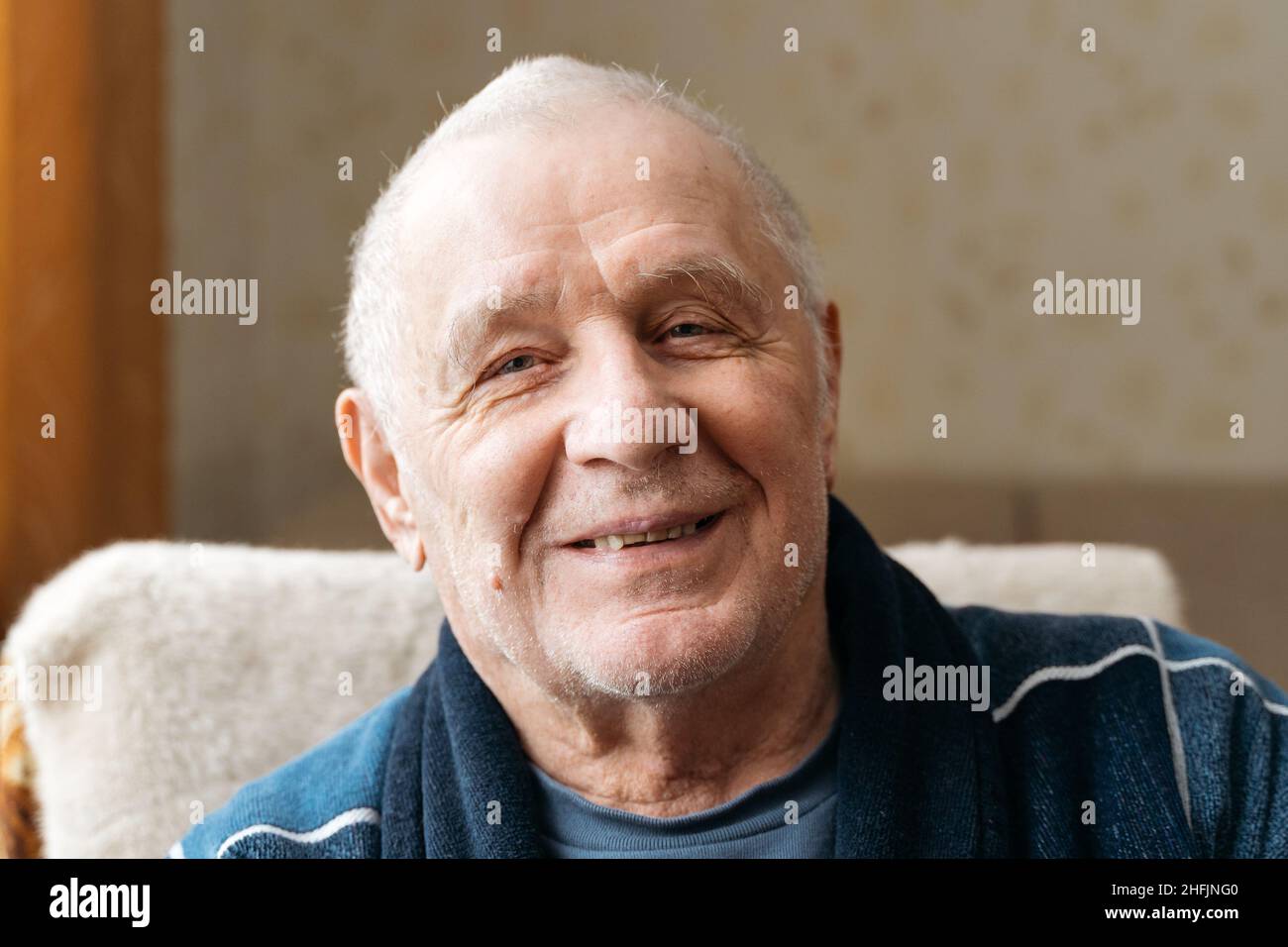 Close up portrait of old smiling man looking at camera. He is open-eyed ...