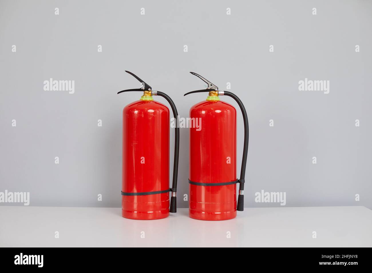 Two red chemical, carbon dioxide or air pressurized water fire extinguishers on a table Stock Photo