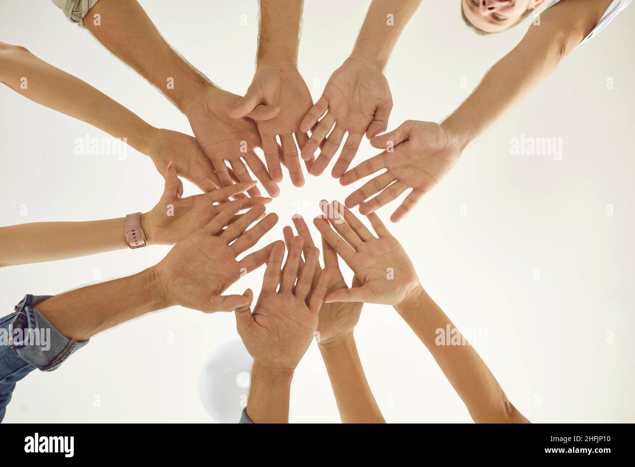 Group of happy young men and women putting their hands together, view from below Stock Photo