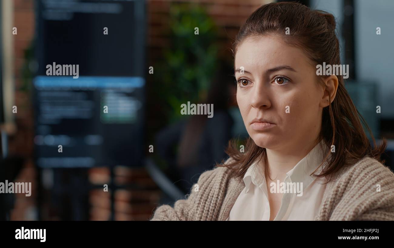 Portrait of caucasian software developer working focused looking at computer screen while typing in it startup office. System engineer writing code with colleagues online cloud computing. Stock Photo