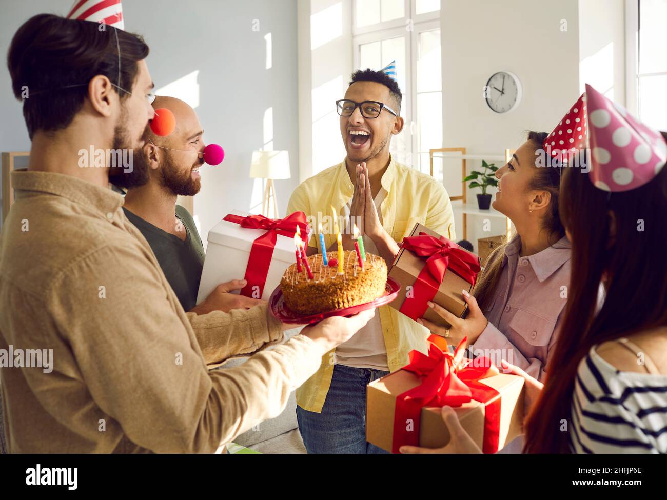 Diverse friends greeting with cake and presents excited mate Stock Photo