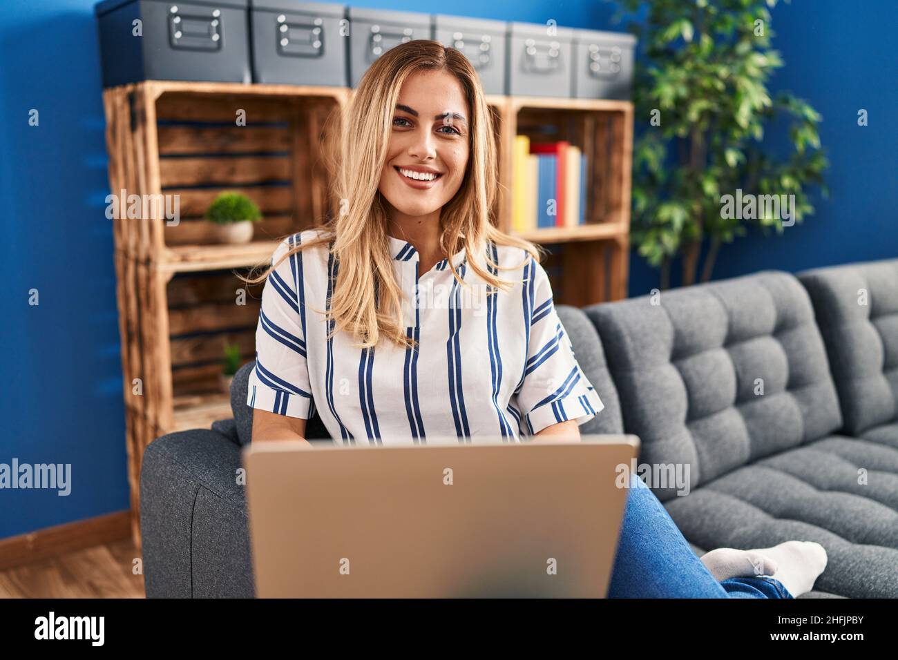 Young blonde woman using laptop sitting on sofa at home Stock Photo - Alamy
