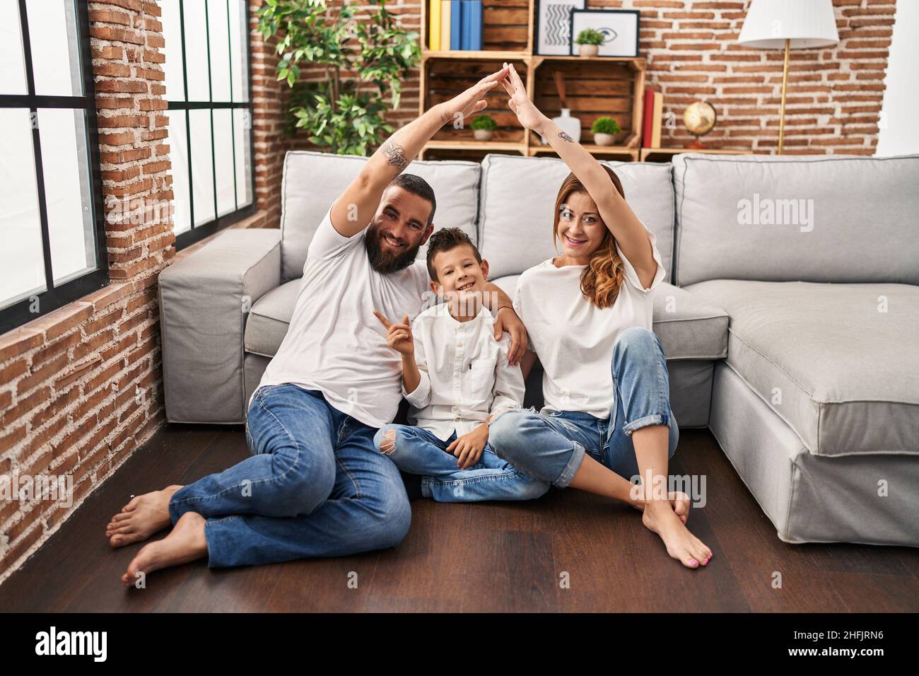 Family of three doing house shape with arms smiling happy pointing with hand and finger to the side Stock Photo