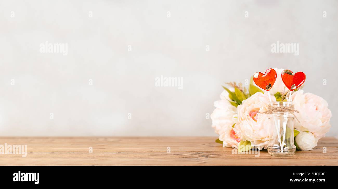 Still life Valentines day festive empty background with 2 red lollipop and pink flowers on wooden table background. Mockup with copy space for design Stock Photo