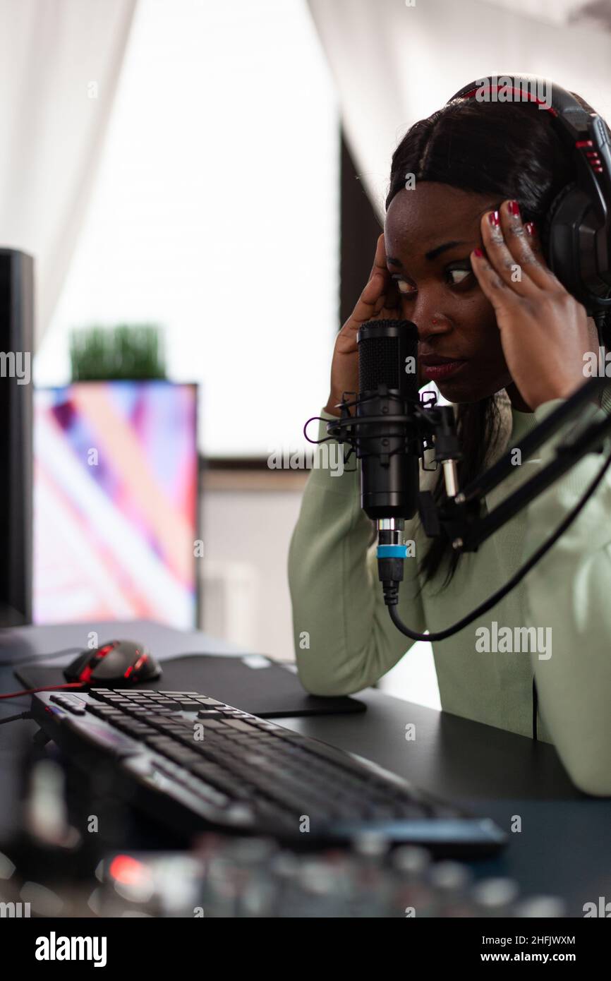 Upset sad pro woman gamer playing space shooter videogames losing online championship. Nervous player talking into microphone during live streaming using RGB computer equipment. Cyber space Stock Photo