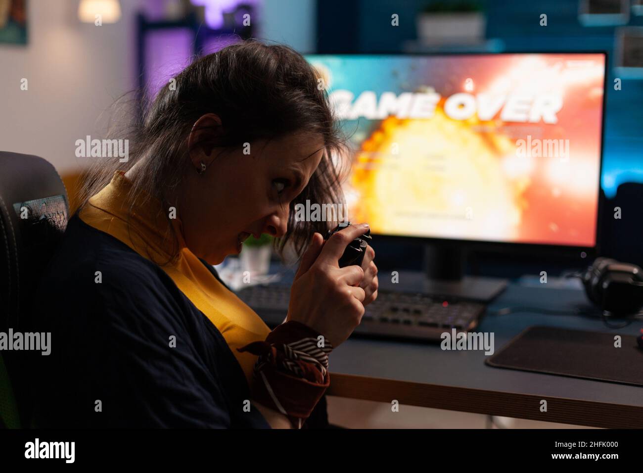 Frustrated gamer playing online video games with controller. Woman using joystick on computer to play internet games and losing. Disappointed person with electronic gaming equipment. Stock Photo