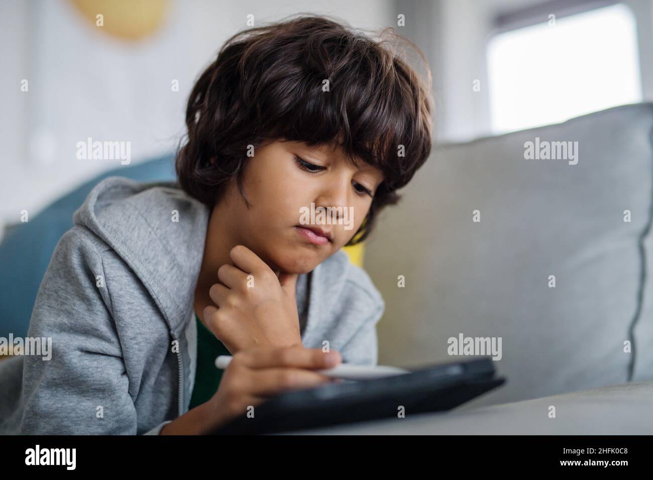 Little multiracial boy with tablet lying on sofa at home Stock Photo ...