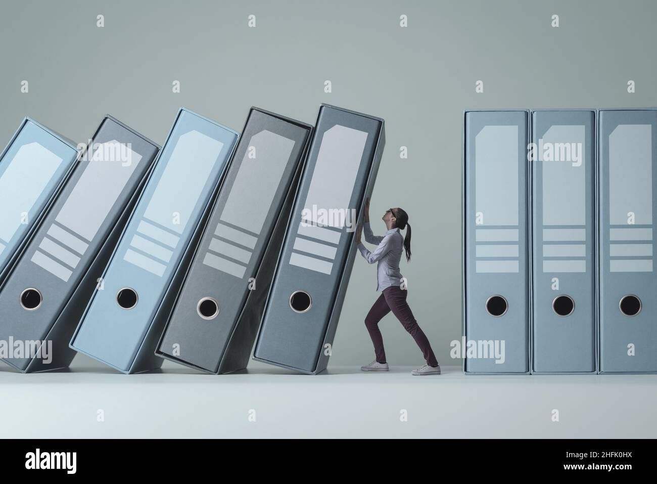 Businesswoman holding and supporting falling ring binders, she is