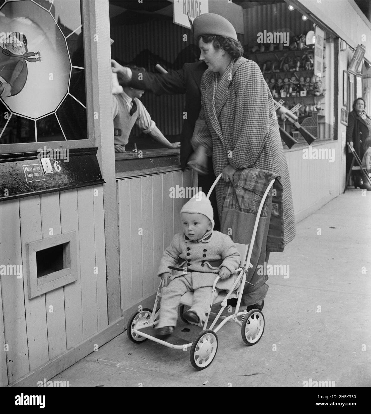 Skegness, East Lindsey, Lincolnshire, 12/06/1948. A woman with a child in a pushchair at an amusement park during a Laing staff outing to Skegness. A group of about 100 people attended this outing from contracts in Grimsby, Carrington's Coppice, East Leake and Leicester. Stock Photo