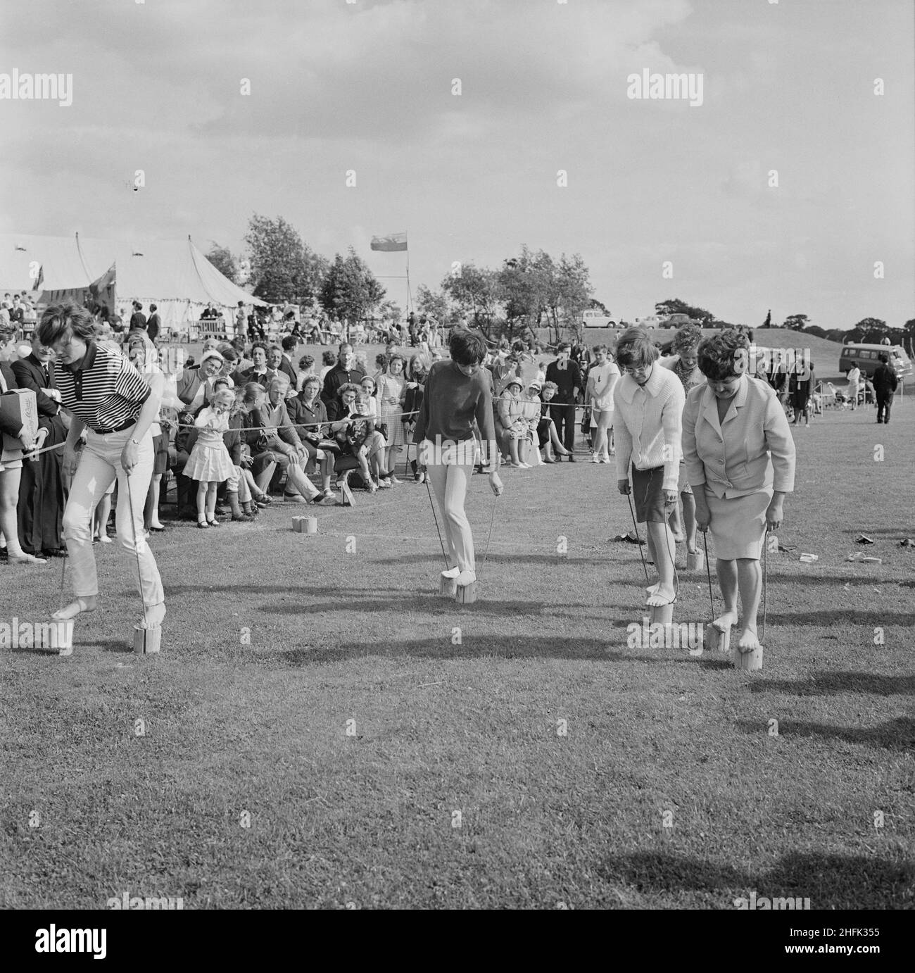 Laing Sports Ground, Rowley Lane, Elstree, Barnet, London, 26/06/1965. Women competing in a flower pot race, with spectators behind a rope fence, at the annual Laing sports day held at the Laing Sports Ground at Elstree. In 1965 Laing's annual sports day was held at the sports ground on Rowley Lane on 26th June. As well as football and athletics, there were novelty events including the sack race and Donkey Derby, and events for children including go-kart races, fancy dress competitions, and pony rides. Stock Photo