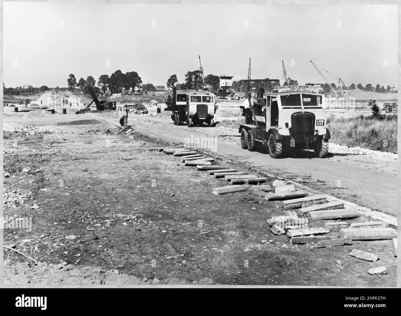 Filton Airfield, South Gloucestershire, 30/04/1950. Rapid Concrete Breaking Co Ltd trucks at Filton Airfield during construction of a runway, with construction work in progress beyond. Laing extended the runway westwards at Filton Airfield to accommodate the Bristol Brabazon airliner, which was being built at the airfield. Work began in July 1946 on the new runway, which was 2,725 yards long and 100 yards wide. The work required the requisitioning and removal of Charlton village and a temporary flying strip was laid, for use while the new runway was under construction. Stock Photo