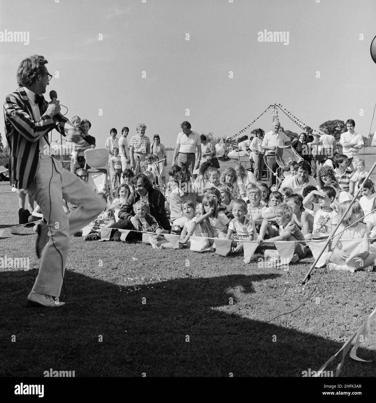 Laing Sports Ground, Rowley Lane, Elstree, Barnet, London, 21/06/1986. A man in a striped jacket, possibly 'Poz the Magician,' entertaining a crowd of children at the 1986 Family Day at Laing's Sports Ground. Over 2500 people attended the Family Day and raised over &#xa3;700 for that year's designated charity The British Heart Foundation.  Attractions included; guest appearances by the cast of the television programme Grange Hill, a bouncy castle, donkey rides, Punch and Judy shows, Pierre the Clown, children's races, blindfold stunt driving and golf and six-a-side football tournaments. Stock Photo
