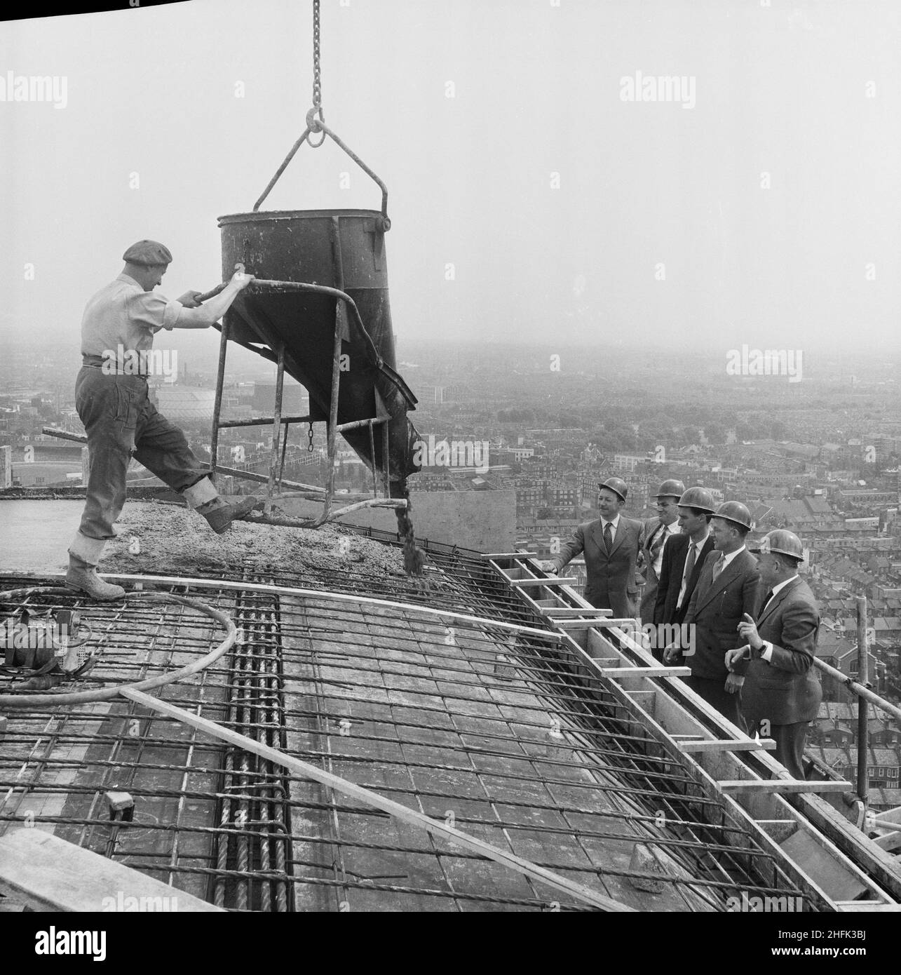 Empress State Building, Lillie Road, Earl's Court, Hammersmith and Fulham, London, 03/07/1961. Managers gathering to watch a worker pour out the topmost load of concrete on the roof of the Empress State Building, Earl's Court, London. The men pictured, left to right are: GE Margetts, Agent, P Clarke, R Hill, C Farrow, General Foreman and W Pitman, District Manager. This photograph was used in the August 1961 issue of Team Spirit, the Laing company newsletter. Stock Photo