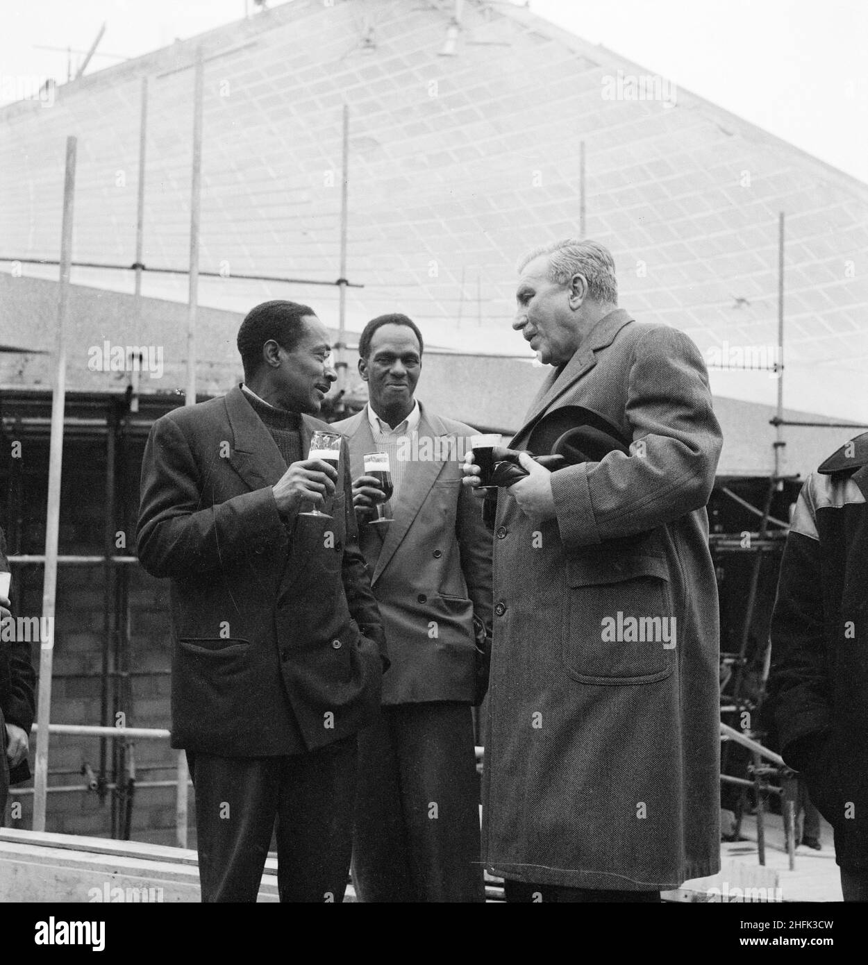 Commonwealth Institute, Kensington High Street, Kensington, London, 22/11/1961. Sir James Robertson, Chairman of the Board of Governors of the Commonwealth Institute (right) and two other men drinking beer at the topping out ceremony reception. Laing built the Commonwealth Institute between October 1960 and October 1962 to replace the former Imperial Institute that was to be demolished to make way for new facilities at Imperial College.  The building consisted of a four-storey administrative block housing a library, restaurant, board room and conference hall and a separate two-storey b lock co Stock Photo