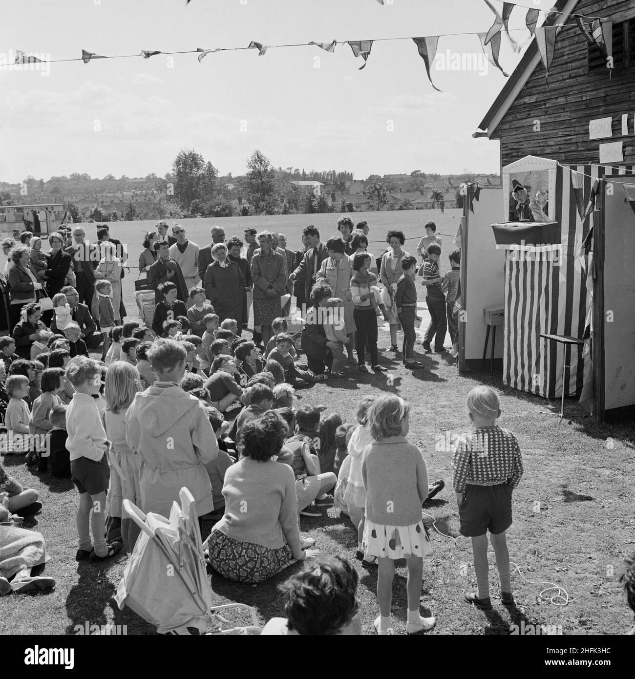 Laing Sports Ground, Rowley Lane, Elstree, Barnet, London, 26/06/1965. Children watching a Punch and Judy show at the annual Laing sports day held at the Laing Sports Ground at Elstree. In 1965 Laing's annual sports day was held at the sports ground on Rowley Lane on 26th June. As well as football and athletics, there were novelty events including the sack race and Donkey Derby, and events for children including go-kart races, fancy dress competitions, and pony rides. Stock Photo