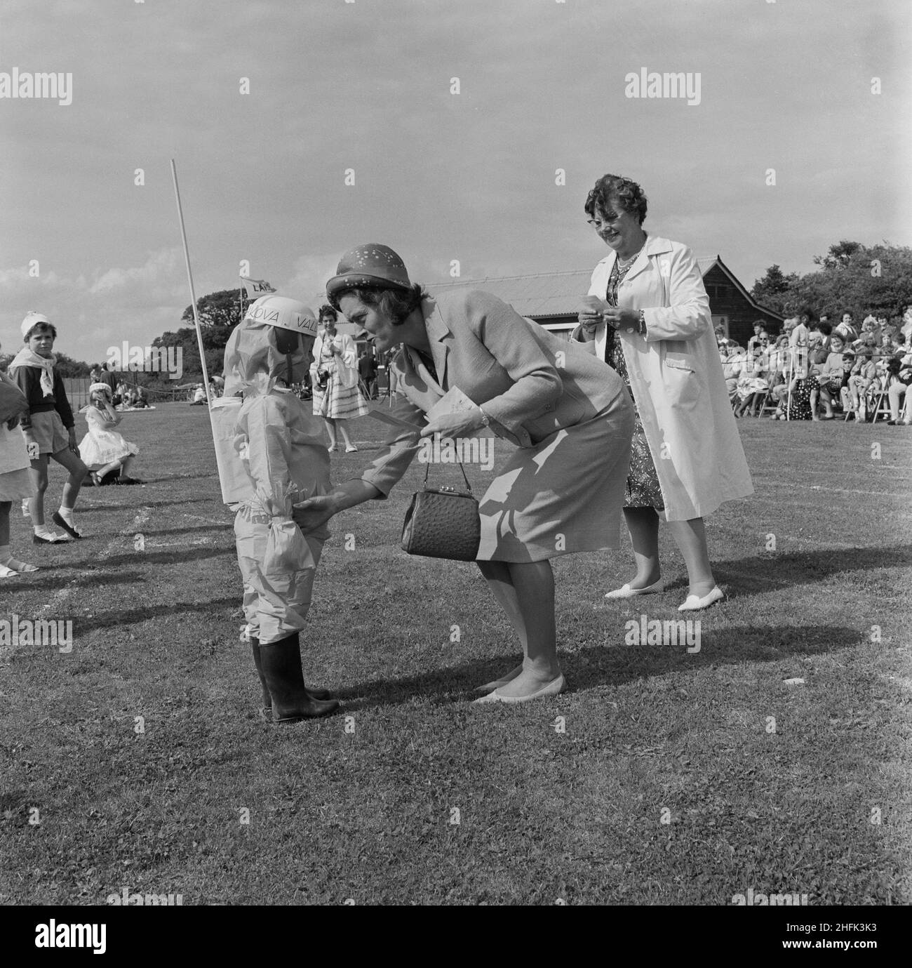 Laing Sports Ground, Rowley Lane, Elstree, Barnet, London, 22/06/1963. A young girl, dressed as the cosmonaut Valentina Tereshkova, receiving a prize from Hilda Laing after a fancy dress competition at the annual Laing sports day at Elstree. In 1964 Laing's annual Sports Day was held at sports ground on Rowley Lane at Elstree on 22nd June. Events included inter-branch tennis, a football competition, an athletic programme, and bowls. There were sport and athletic events for children, as well as fancy dress competitions. A week before this photograph was taken, Valentina Tereshkova became the fi Stock Photo