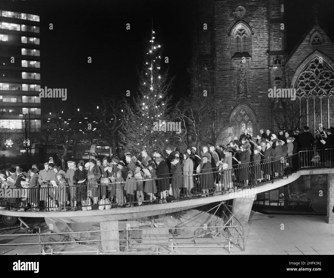 Bull Ring Centre, Birmingham, 23/12/1963. A carol service being held on the spiral ramp at the Bull Ring Centre, with the Church of St Martin in the background. Stock Photo