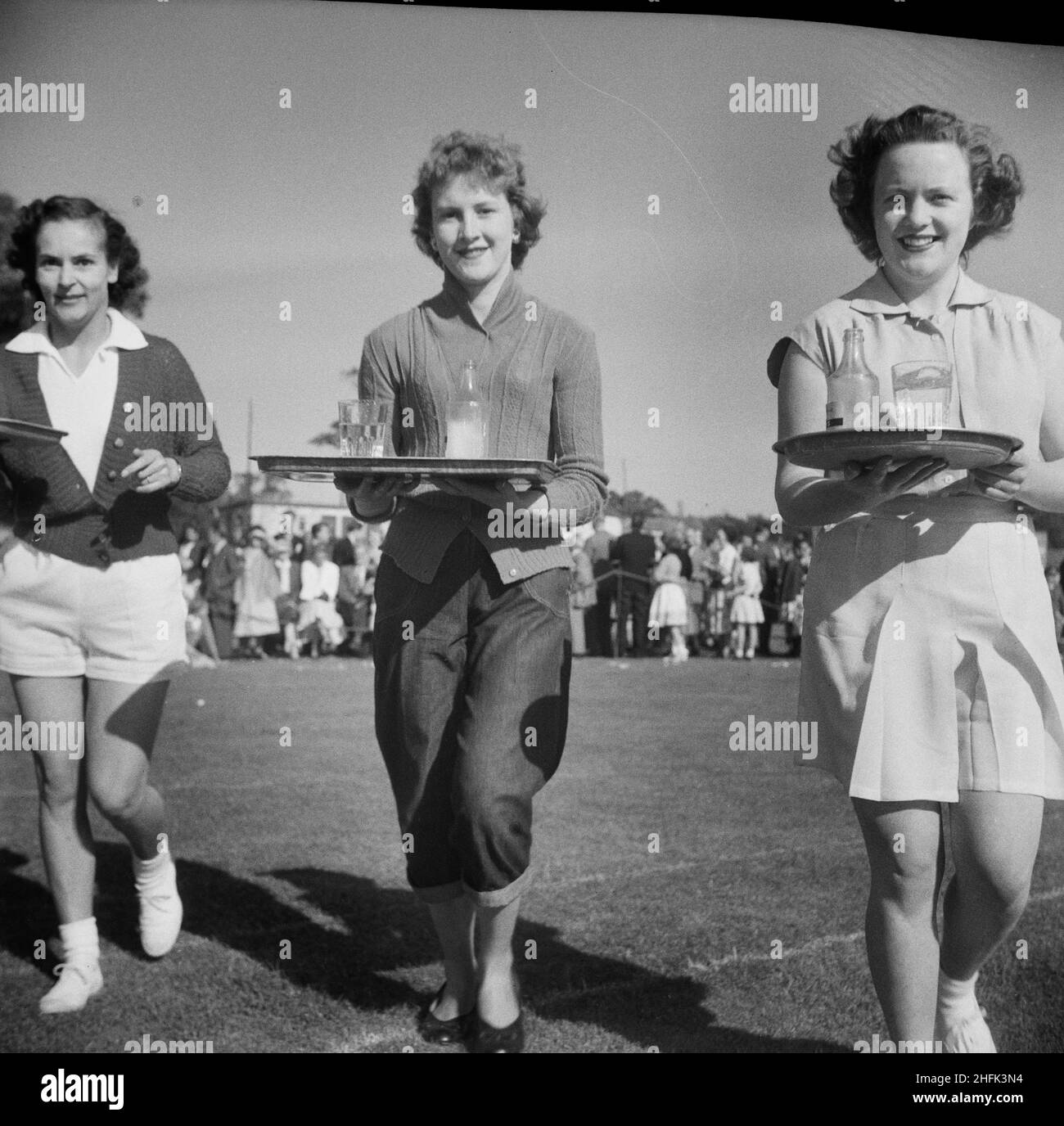 Laing Sports Ground, Rowley Lane, Elstree, Barnet, London, 18/06/1955. Three women with trays of refreshments competing in a waitressing race during a Laing sports day at Elstree. This sports day was attended by people from Laing contracts in Thurleigh, Bradford, Harlow, Shell Haven, London, Welwyn Garden City, Leicester and even as far as Plymouth. The day included field and track competitions as well as special attractions including Scottish dancing, a flower show, gymnastic displays and music by the Silver Band of the 5th Hendon Company Boys' Brigade. Stock Photo