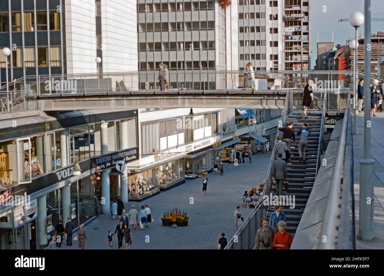 A view of the Sergelgatan pedestrian shopping precinct below the Hötorget buildings (on the left) in the central Norrmalm district, Stockholm, Sweden in the 1960s. The pedestrian footbridge over the shopping mall seems to have since been removed. In the background new buildings are being constructed. The Hötorget buildings are five modernist high-rise office blocks. This image is from an amateur 35mm colour transparency – a vintage 1960s photograph. Stock Photo