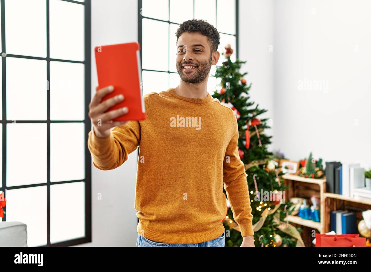Arab Man Tree Young arab man using touchpad standing by christmas tree at home Stock ...