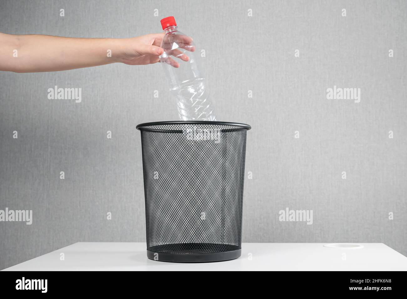 hand of an unrecognizable woman throws a plastic bottle into the trash ...