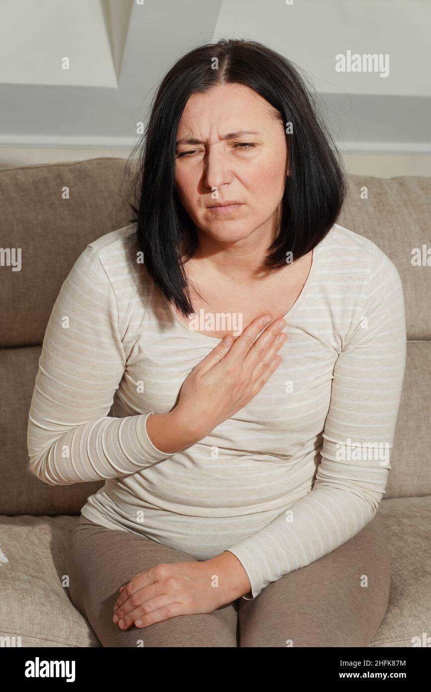 Middle aged mature woman having a heart attack. Woman suffering from chest pain. Health care and cardiological concept. Stock Photo