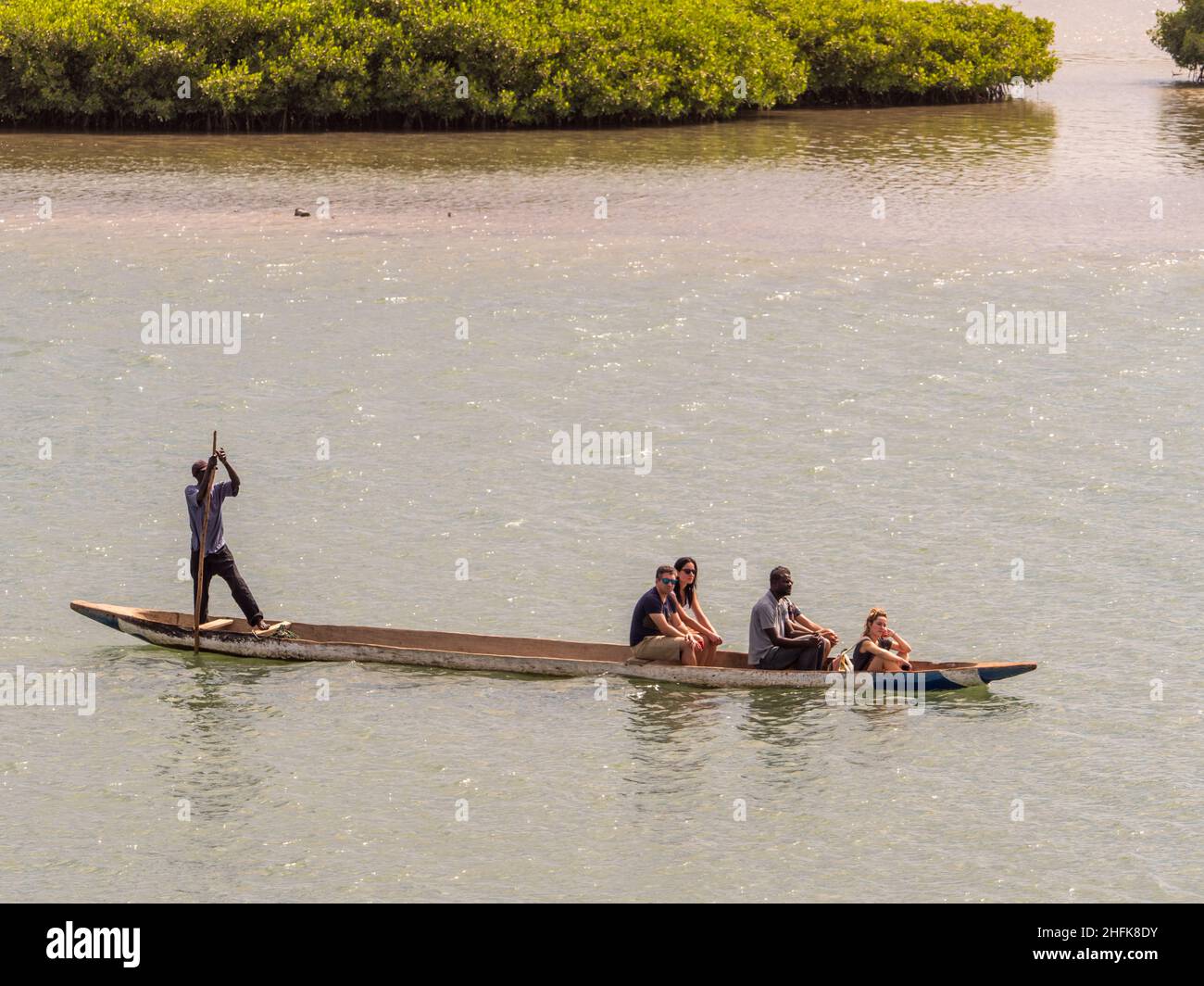 Joal-Fadiouth, Senegal, Africa - Jan 2019: An African man ushes himself off with a pole on a small wooden canoe in the sea between Joel and Fadiouth - Stock Photo