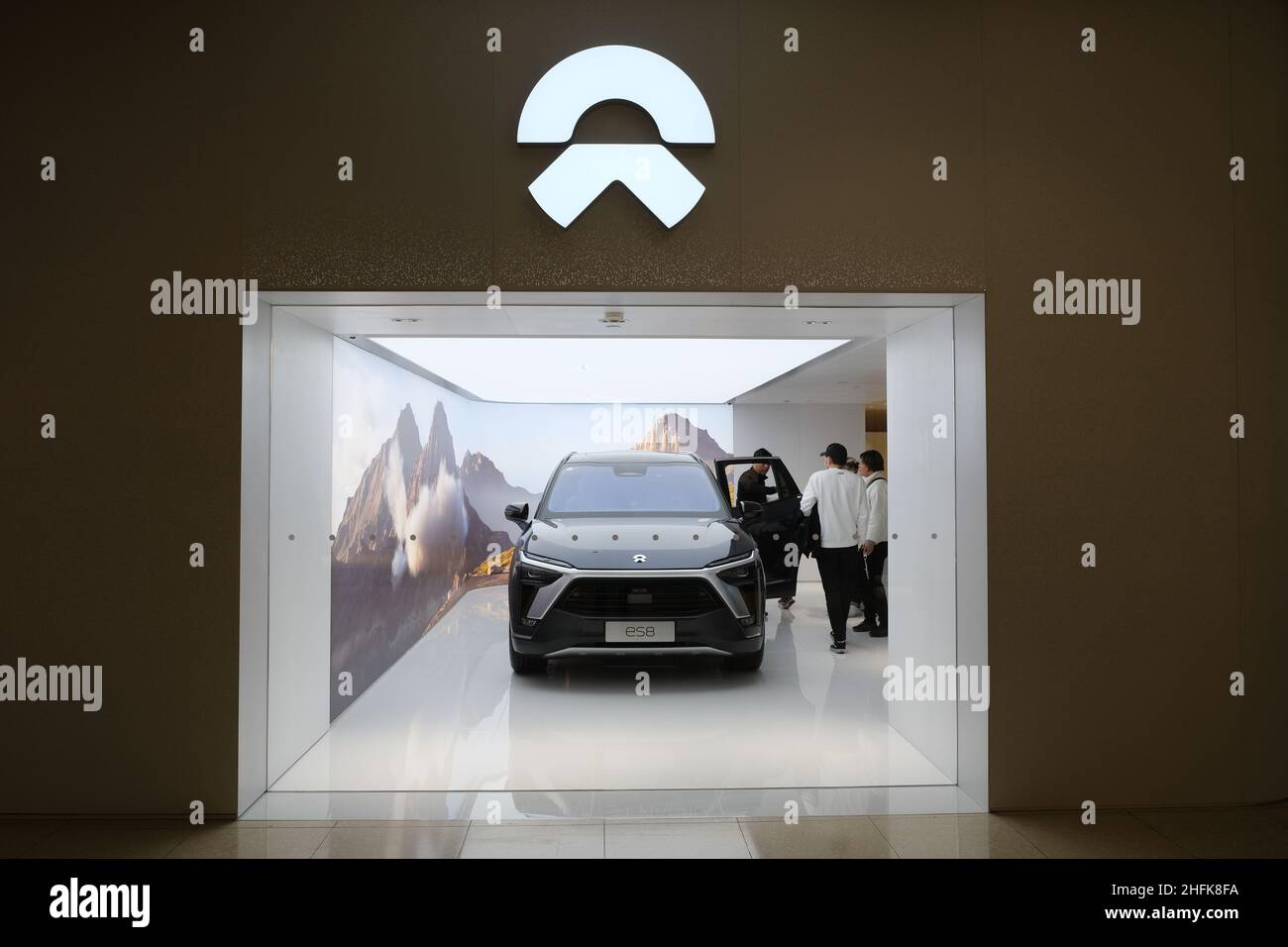 NIO EV store logo. NIO electric car and Chinese customers in store