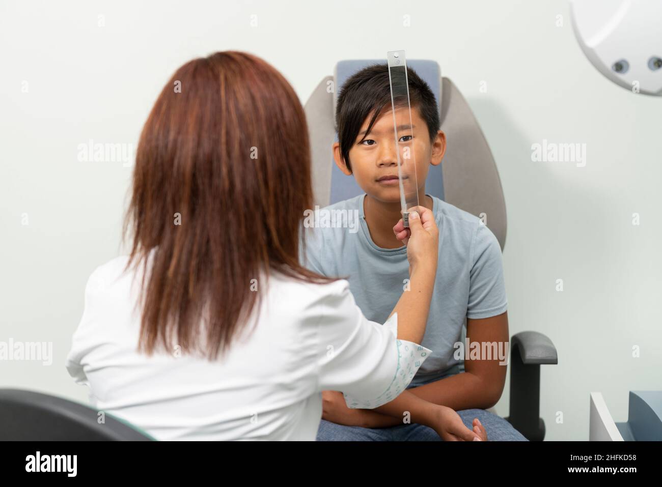 Asian boy in a consultation of an ophthalmologist woman with a prism Stock Photo