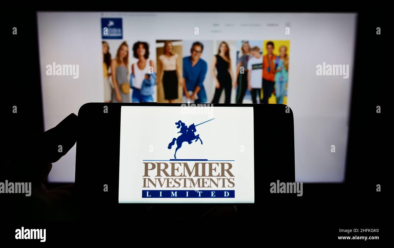 Person holding smartphone with logo of Australian company Premier
