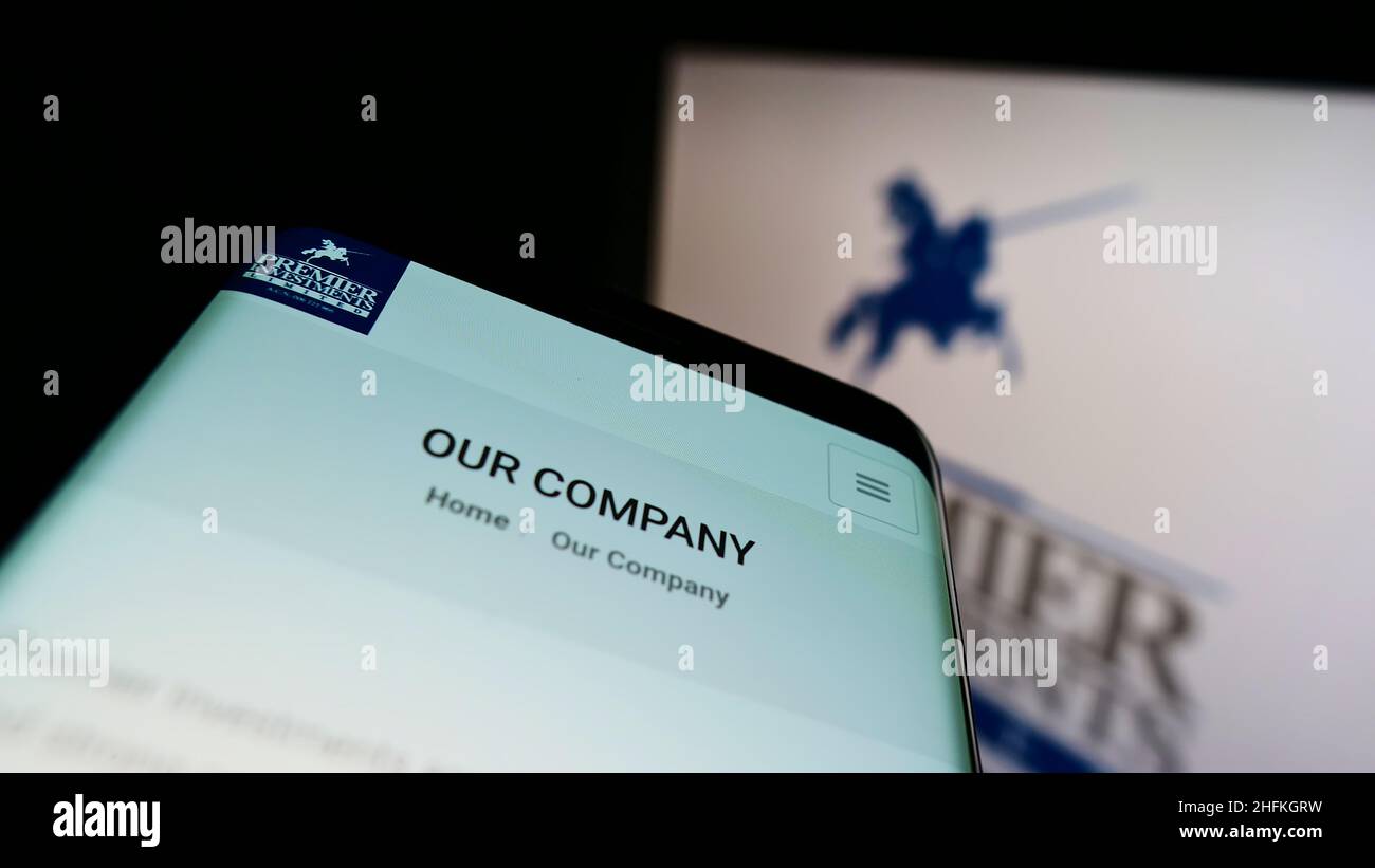 Mobile phone with website of Australian company Premier Investments Ltd. on screen in front of business logo. Focus on top-left of phone display. Stock Photo