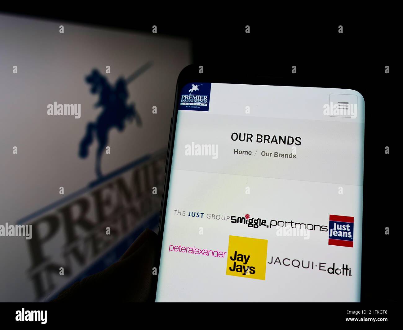 Person holding cellphone with webpage of Australian company Premier