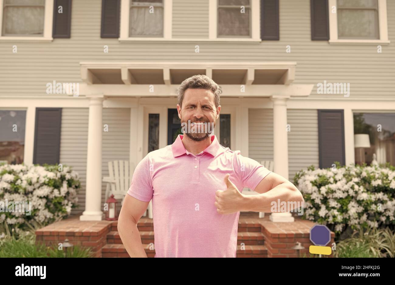 happy owner show thumb up. ownership. confident man outside new american home. Stock Photo