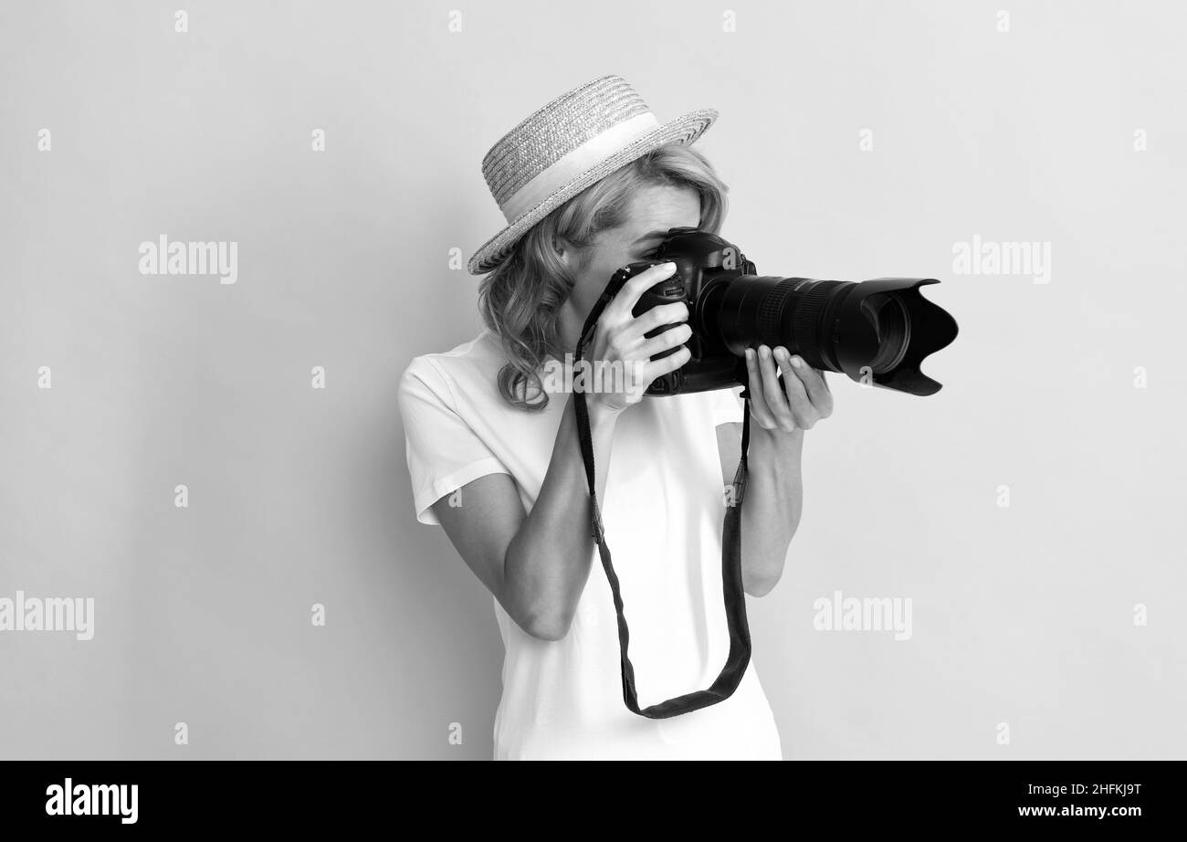 professional woman photographer with camera in straw hat making photo, photographing Stock Photo