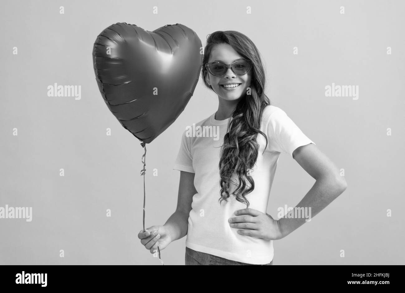 happy kid in sunglasses hold red heart party balloon for valentines day love symbol, love Stock Photo