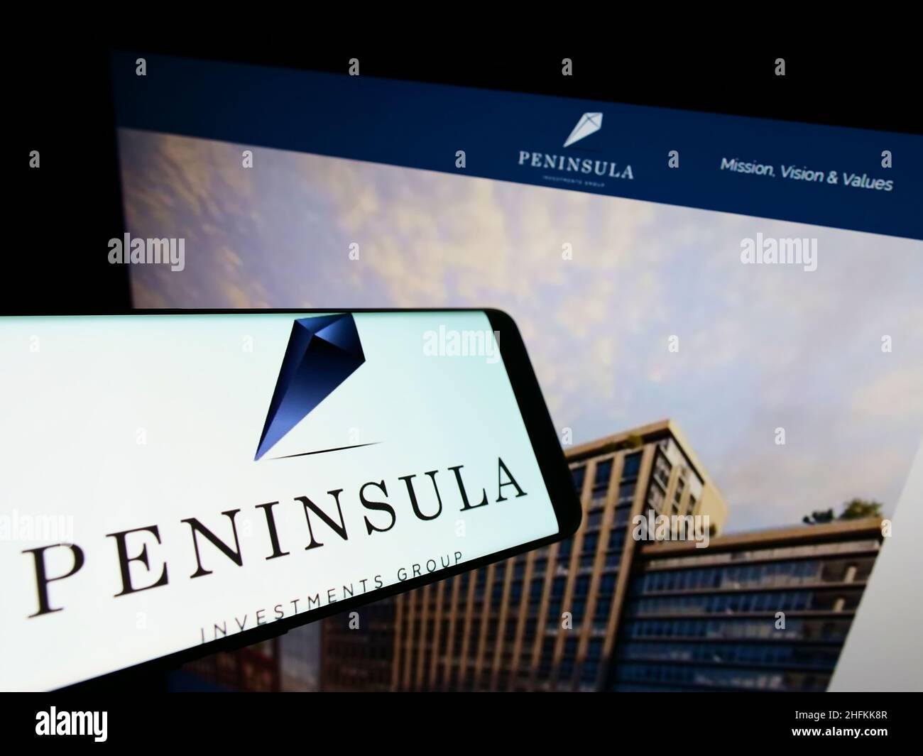 Smartphone with logo of company Peninsula Investments Group Capital LLC on screen in front of website. Focus on center-right of phone display. Stock Photo