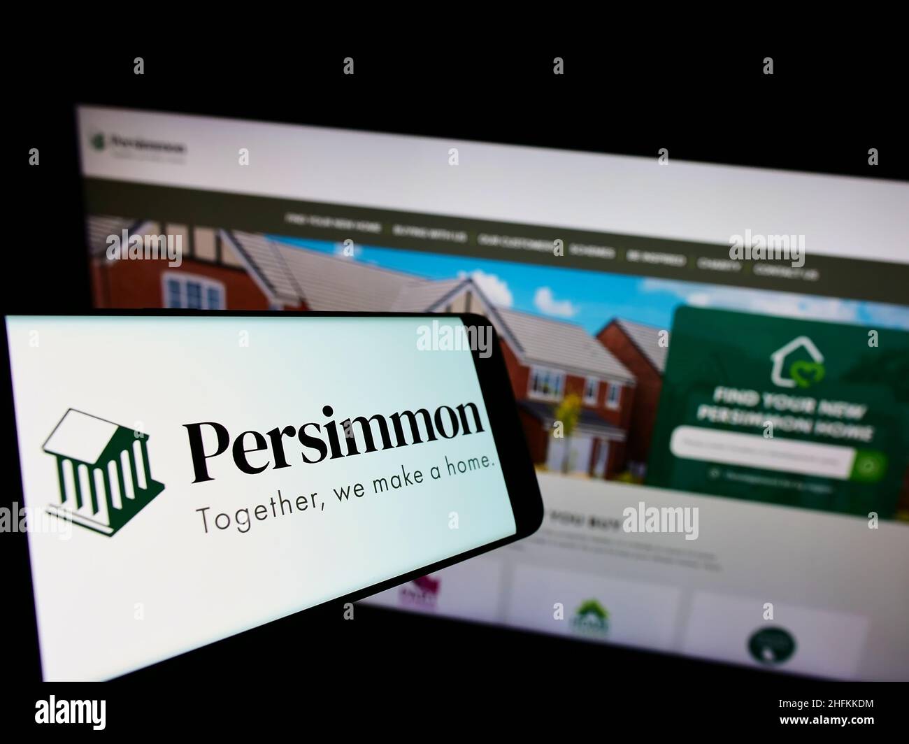Cellphone with logo of British housebuilding company Persimmon plc on screen in front of business website. Focus on center of phone display. Stock Photo