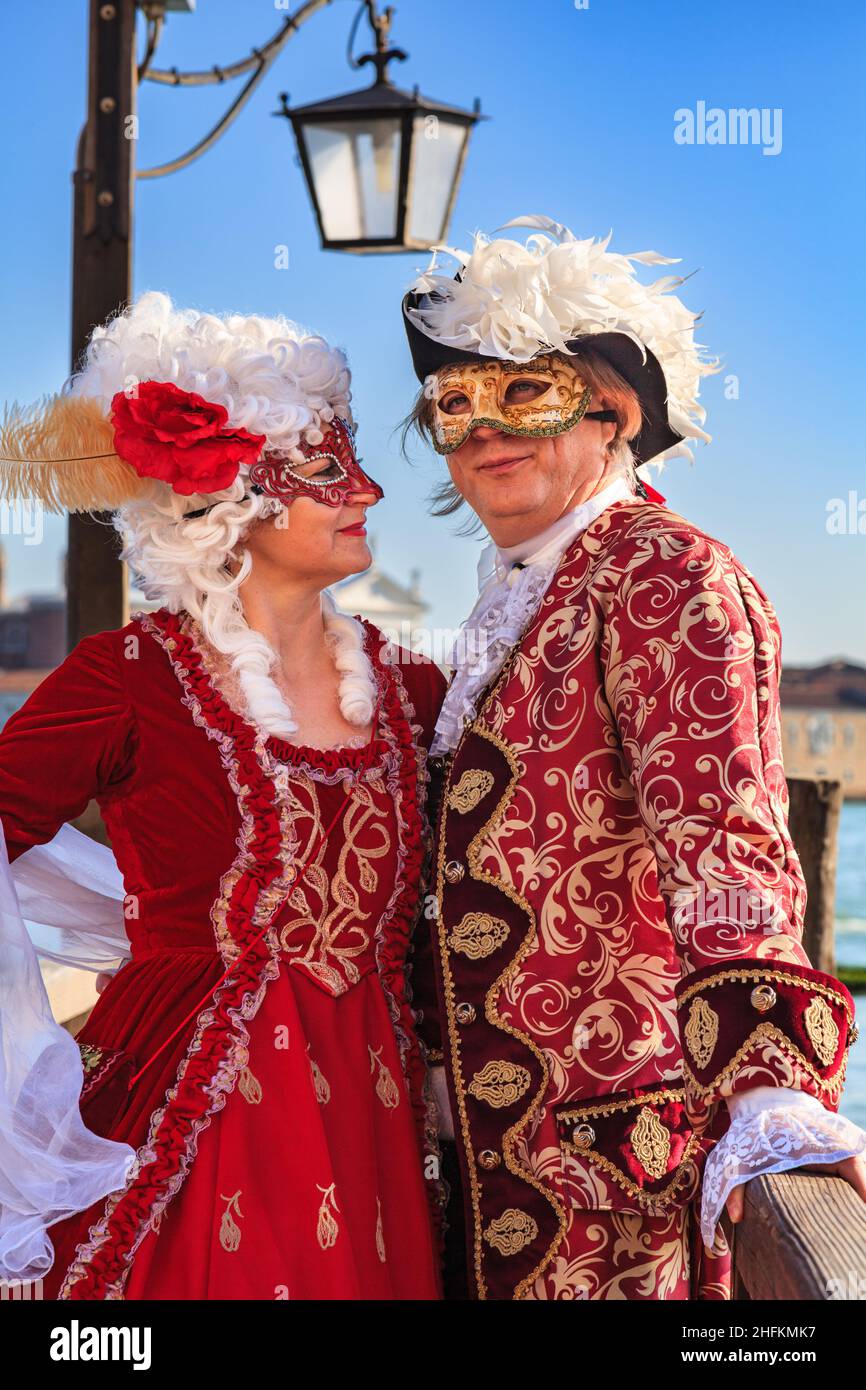 Man and woman in  historic Venetian fancy dress baroque costume, pose by the lagoon at Venice Carnival, Carnevale di Venezia, Italy Stock Photo